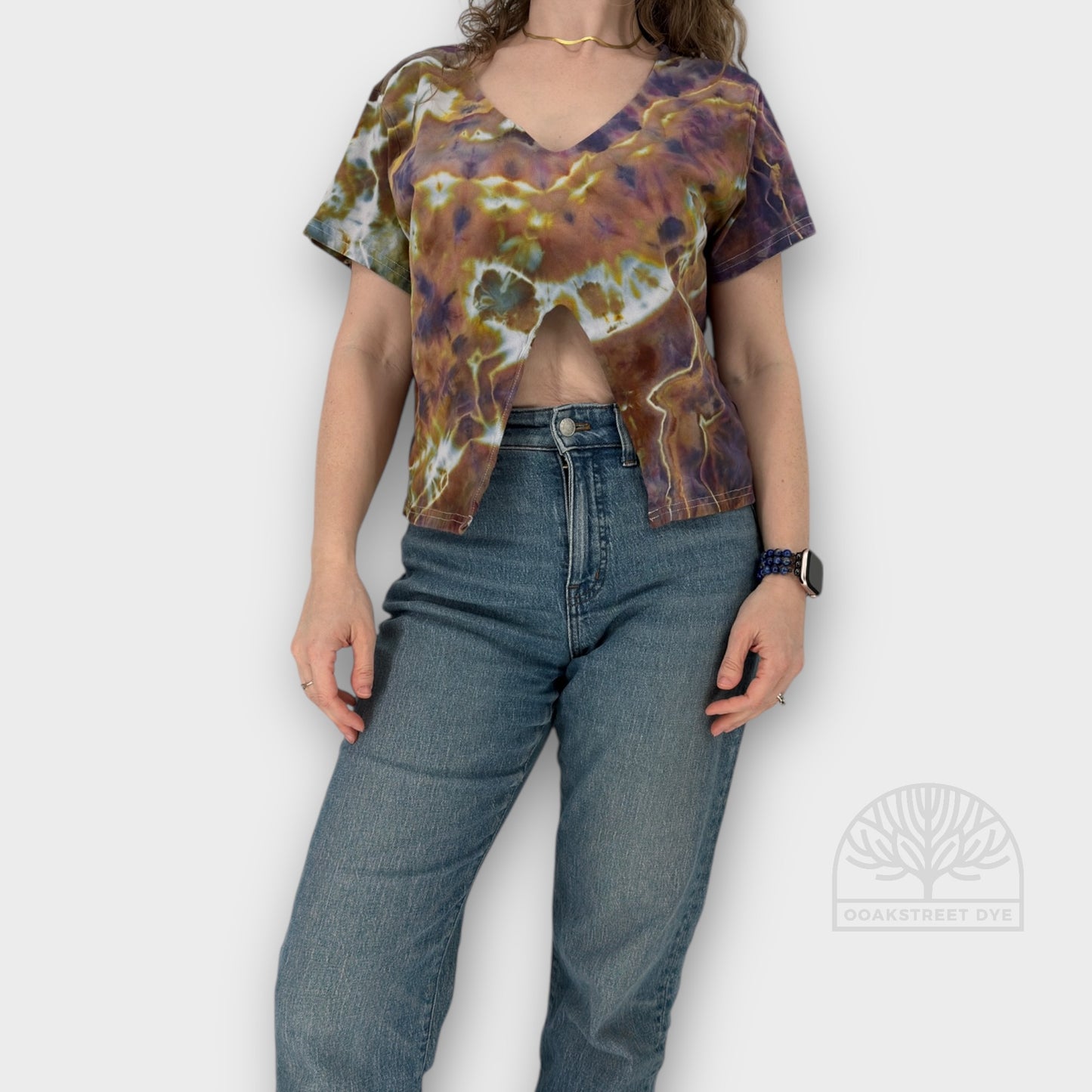 Person wearing a tie-dye shirt and blue jeans on a plain background