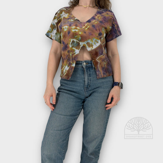 Person wearing a tie-dye shirt and blue jeans on a plain background