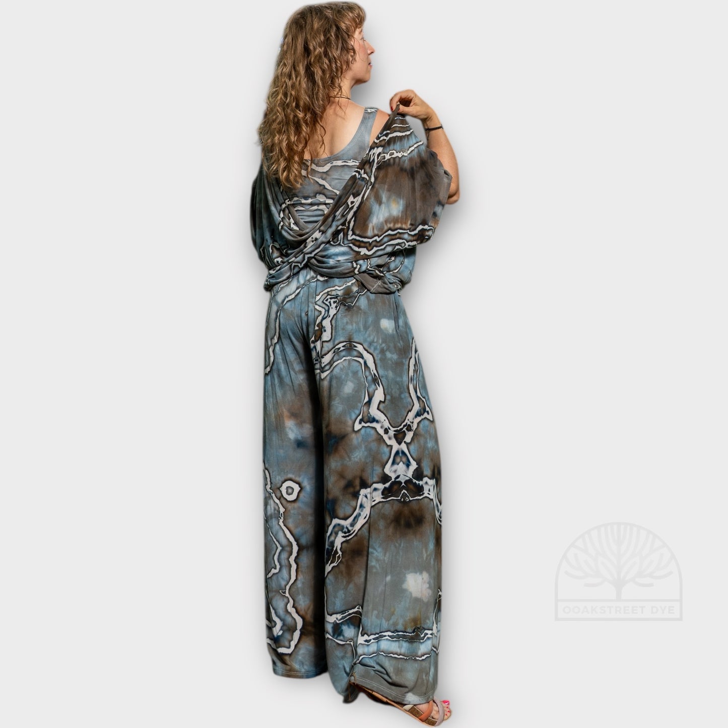 Back view of Driftwood two-piece set featuring twist top and wide-leg palazzo pants in hand-dyed blue-gray, charcoal, and earthy brown tones.
