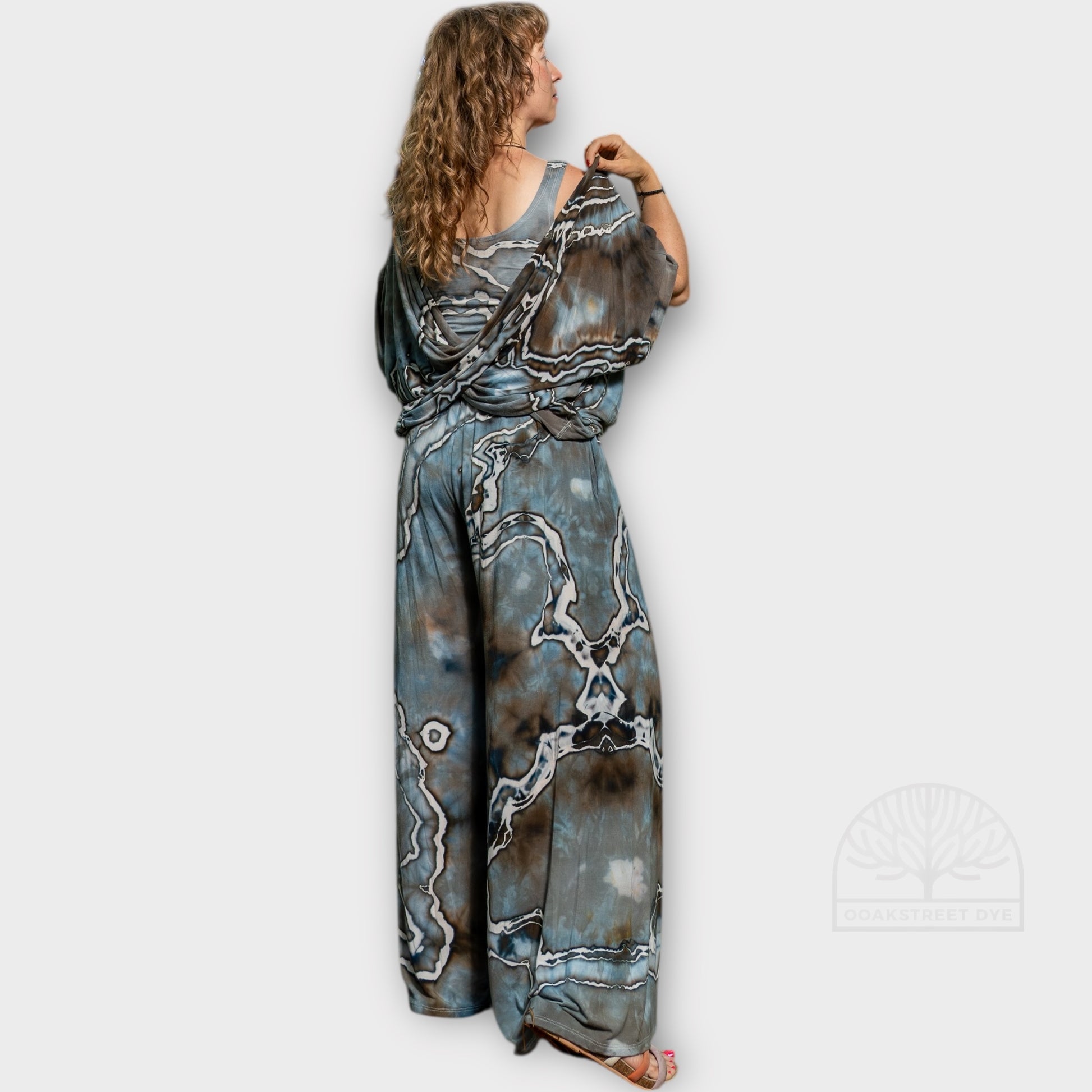 Back view of Driftwood two-piece set featuring twist top and wide-leg palazzo pants in hand-dyed blue-gray, charcoal, and earthy brown tones.